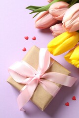 Beautiful fresh tulips with a gift box on color background