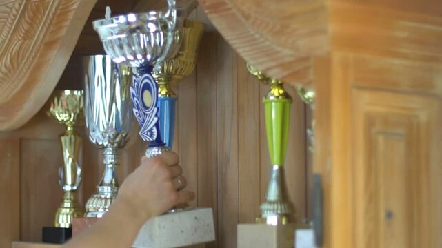 Beautifull young woman puts the trophy on the shelf. Sportswoman recived award. 
