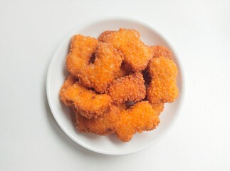 Fried chicken nuggets in a white plate on a white background. Top of view. 