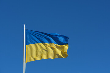 A vibrant Ukrainian flag flutters against a bright blue sky, showcasing the blue and yellow colors that represent the nation. This captures a moment of unity and hope.
