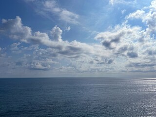 Wide blue ocean and fluffy clouds in blue sky 
