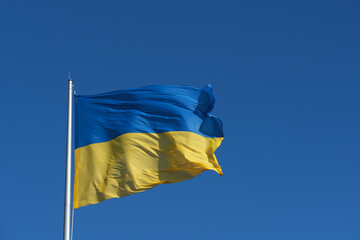 A vibrant Ukrainian flag flutters against a bright blue sky, showcasing the blue and yellow colors that represent the nation. This captures a moment of unity and hope.
