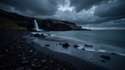 Obraz premium A serene vista of a vast black sand beach, dotted with pebbles, stretches towards a gently flowing body of water on the right. Leftward, the dramatic expanse of ebony grains meets rugged stones under 