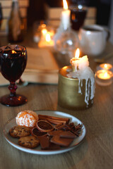 Books, lit candles, red wine, snacks and various deocration on the table. Dark academia or Halloween concept. Selective focus.