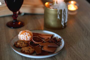 Books, lit candles, red wine, snacks and various deocration on the table. Dark academia or Halloween concept. Selective focus.