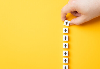 Hand making a row of arrows on a yellow background. Space for text. Paving the way, making plans....
