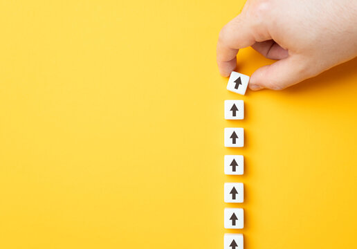 Hand making a row of arrows on a yellow background. Space for text. Paving the way, making plans. Next steps and vision. Course to go forward.
