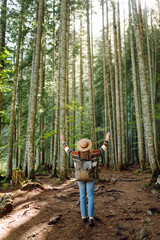 Woman with backpack hiking outdoors in the Forest. Trekking in the Pine Woods. Hiking, recreation and sports in nature.