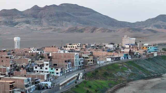 Square brick buildings in a poor, isolated town in a desert with mountains and emptiness in the background. Rough terrain