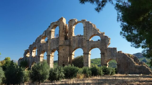 Aqueducts of the ancient city of Aspendos. Ancient aqueducts surrounded by olive trees. Antalya city. Turkey - 4k video 