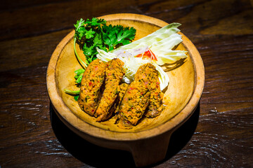 Coconut smoked Chinag Rai curry sausage served in wooden bowl