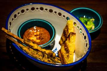 Chicken satay with cucumber relish , peanut sauce and toasted brioche served in bowl