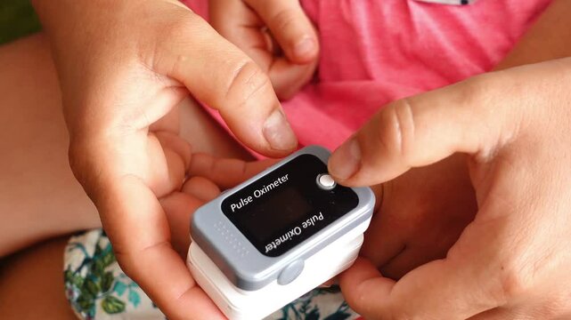 Mother measuring oxygen saturation with pulse oximeter of her child. Coronavirus prevention. Protection against covid 19
