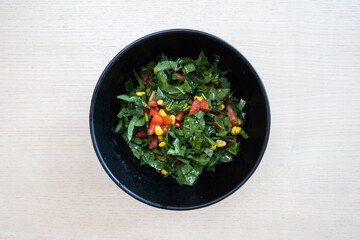A bowl of spinach and tomato salad.