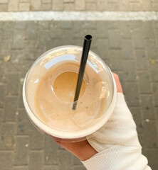 Top view of a cold coffee drink in a plastic cup with a black straw.