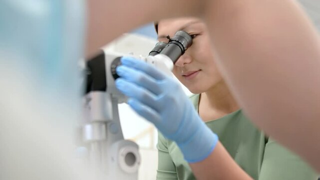 Gynecologist examines a patient using microscope in a gynecological chair. Doctor performs a colposcopy on a young girl in a modern medical office. Prevention and diagnosis of cervical cancer.
