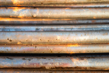 Stack of pipeline of tubing pipe in dirty condition that used in the oil production industrial. Close-up and selective at the object.