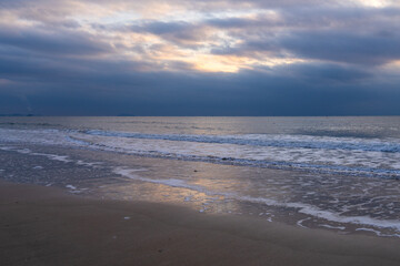 tranquil seascape with surfs on the beach during sunset