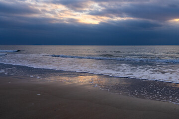tranquil seascape with surfs on the beach during sunset