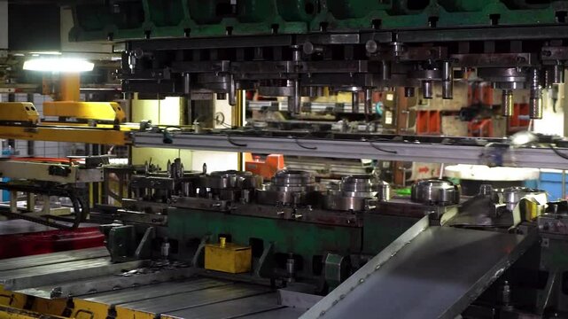 Close up view of a large hydraulic transfer press line shaping metal parts in a factory.