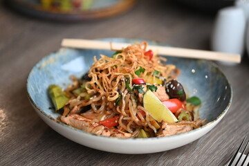 A close-up shot of a healthy, vibrant dish featuring Konjac noodles with tender chicken and a variety of fresh vegetables.