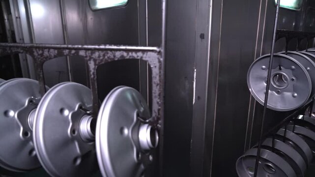 Dipping hanged metal parts in the electropaint tank for the cataphoresis or paint process on the automated conveyor in a factory.