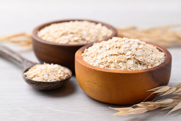 Oat flakes in wooden bowl with spoon, Food ingredient in oatmeal, muesli or porridge