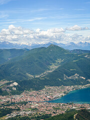 Fototapeta premium Areal view of town Sarnico and turquoise Lake Iseo in Italy and Swiss Alps with snow in mountaintops in the background.