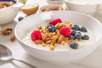 Healthy breakfast bowl with Greek yogurt with granola, fresh blueberries, raspberries and almonds