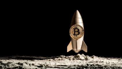 Obraz premium metallic rocket with Bitcoin symbol is launching from sandy surface, symbolizing rise of cryptocurrency and innovation in technology