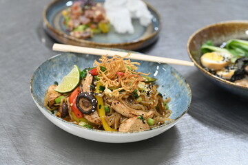 A close-up shot of a healthy, vibrant dish featuring Konjac noodles with tender chicken and a variety of fresh vegetables.