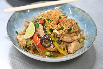 A close-up shot of a healthy, vibrant dish featuring Konjac noodles with tender chicken and a variety of fresh vegetables.