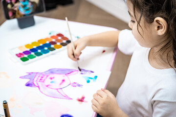  child painting a picture with school supplies, preschool child painting, child drawing a rainbow, child doing homework.