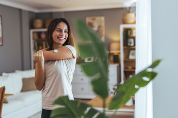 Smiling Woman Stretching Indoors With Health Patch On Arm