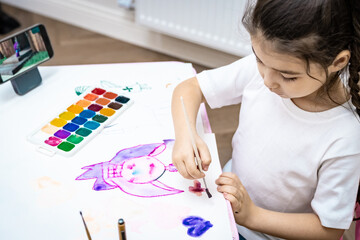  child painting a picture with school supplies, preschool child painting, child drawing a rainbow, child doing homework.