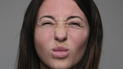 Close up of girl's squinting showing facial wrinkles. Woman making a scrunched face, puckering lips and squinting with visible facial lines.