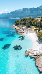 Obraz premium Crystal-clear turquoise water meets a pristine beach, backed by lush greenery and majestic mountains.