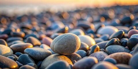 Obraz premium A macro shot of a single, dark grey pebble nestled among larger rocks on a rugged beach at dawn, rock formations, beach, natural world