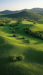 Obraz premium Rolling green hills and distant mountains under a clear sky. A serene landscape.