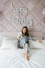 Fototapeta premium Woman celebrating birthday with her dog in bedroom