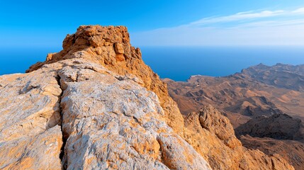 Panoramic view from mountain peak overlooking ocean and desert landscape.