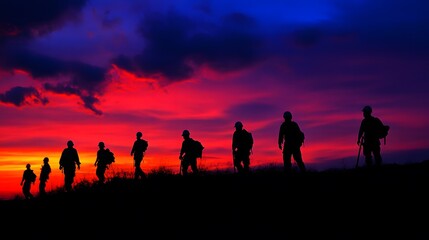 Fototapeta premium Silhouetted Hikers Walking at Sunset Over a Hill