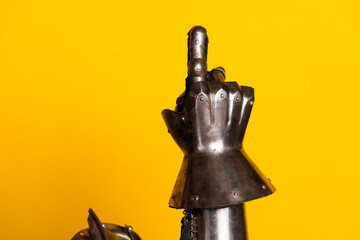 A knight's armored hand gesturing on a vibrant yellow background conveying medieval bravery