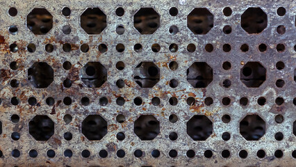 Indusgtrial background texture of a rusted and weathered metal grate with various sized holes
