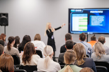 Audience listening to speaker presenting data during business conference. Engaging discussion on...