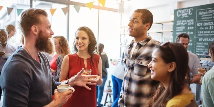 Group of diverse people socializing at a casual gathering. They are chatting, smiling, and enjoying drinks in a lively, friendly atmosphere. Diverse people mingle at gathering and social event.