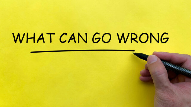 Hand writing What Can Go Wrong text on yellow cover board