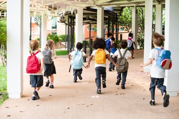 Group of children with backpacks walking to school. Kids in uniforms, diverse group, outdoor setting. School, backpacks, children, diverse group. Cute little kids with backpacks in school.