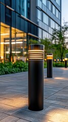 Close-up view of sleek black bollards with LED lights set on stone pavement by an office building under bright daylight