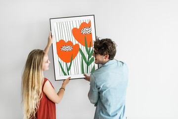 Couple hanging picture frame on a wall
